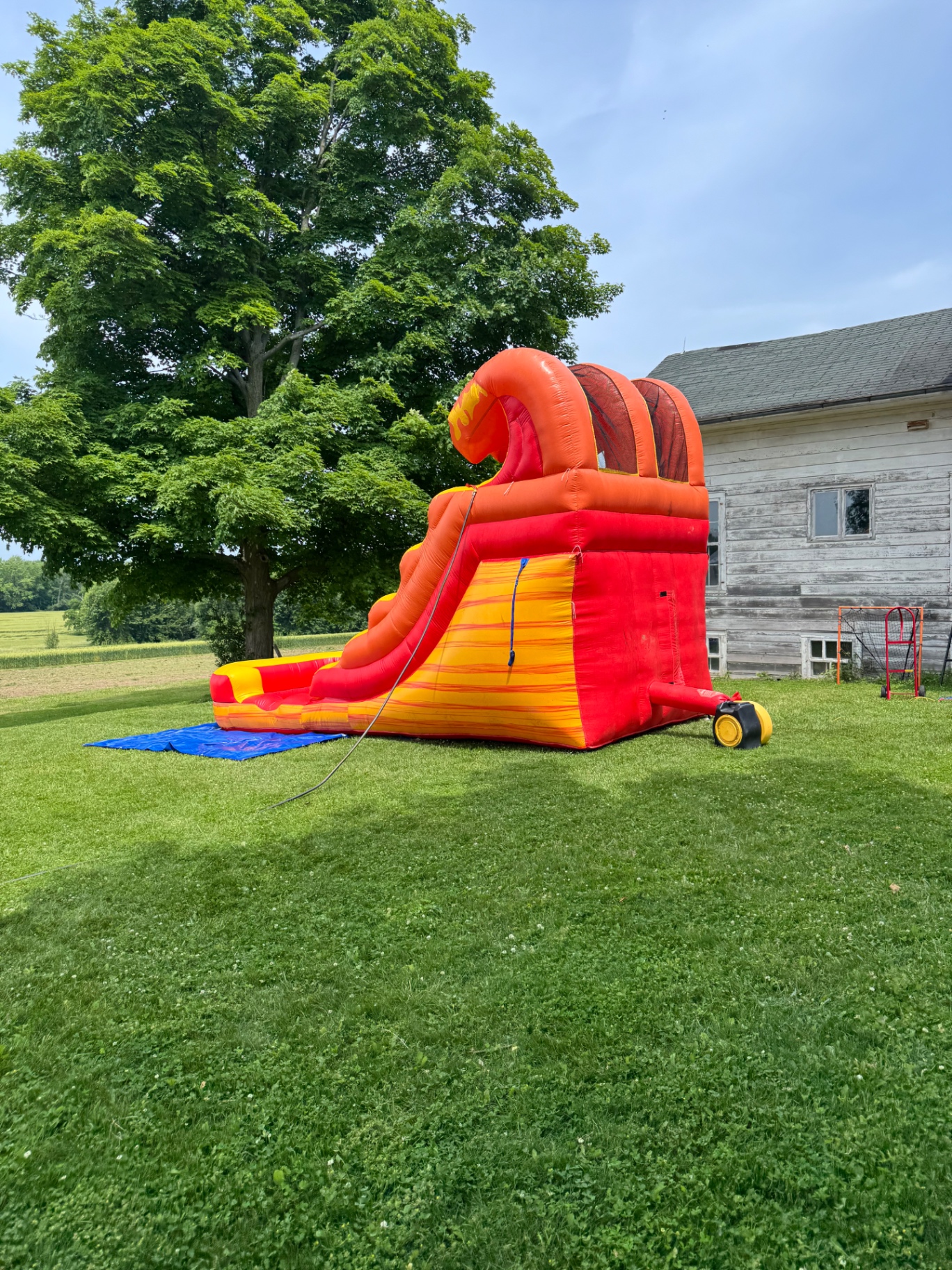 Large red and yellow inflatable slide setup on open grass