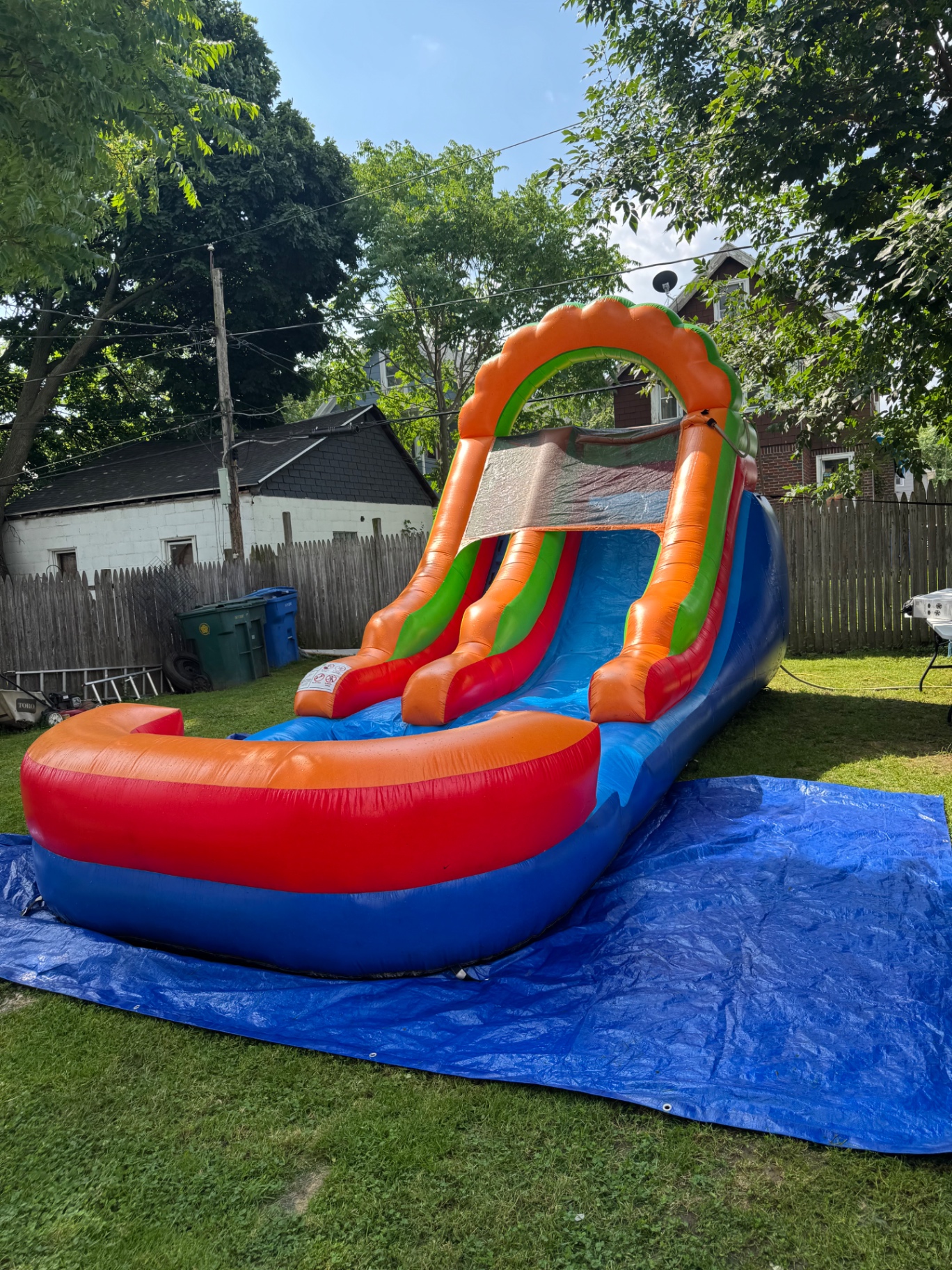 Side angle of orange and blue inflatable water slide on a blue tarp