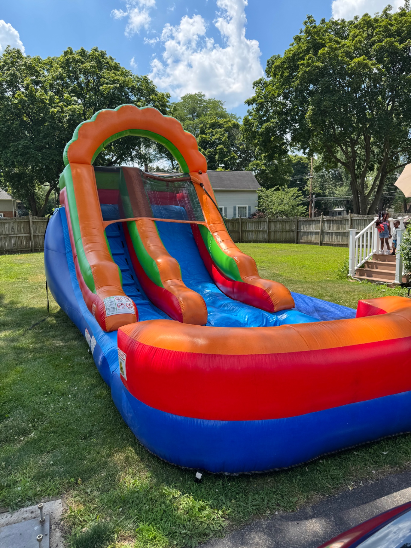 Orange and blue inflatable water slide setup in a backyard