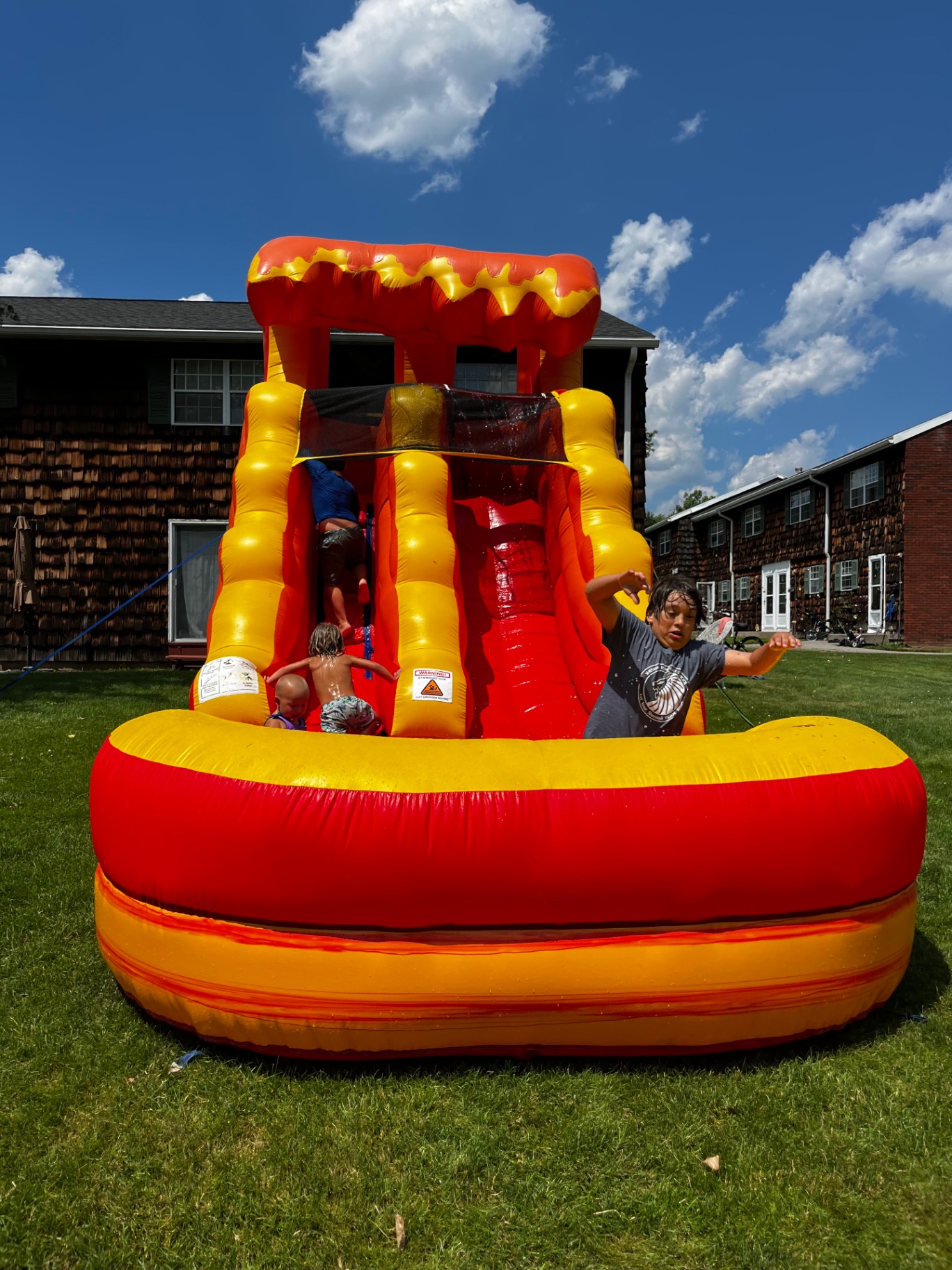 Kids enjoying a red and yellow inflatable water slide outdoors